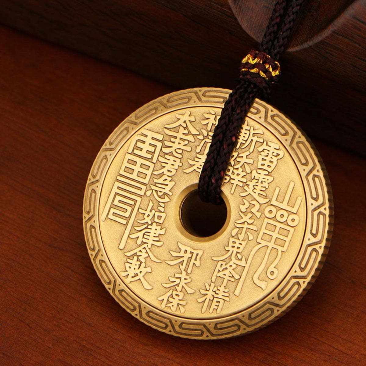 P2 brass ratchet coin with raised Chinese lettering, a patterned rim and a pendant cord through its center.