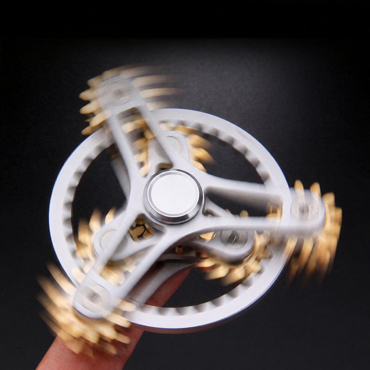 Silver-tone open-frame gear-linked spinner shown spinning between fingertips