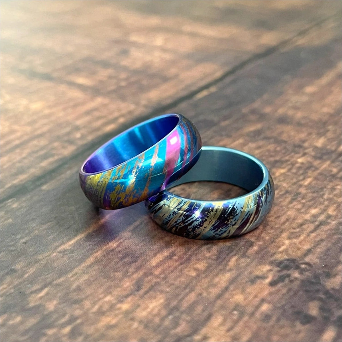 Anodized Titanium Band Ring: two blue multicolor rings resting on wood (gallery view 02).