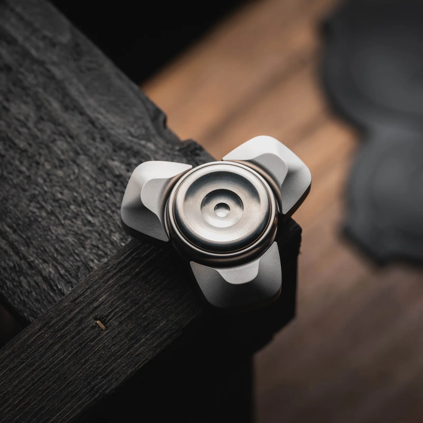 Blacktopworks Dark River metal fidget spinner on dark wood