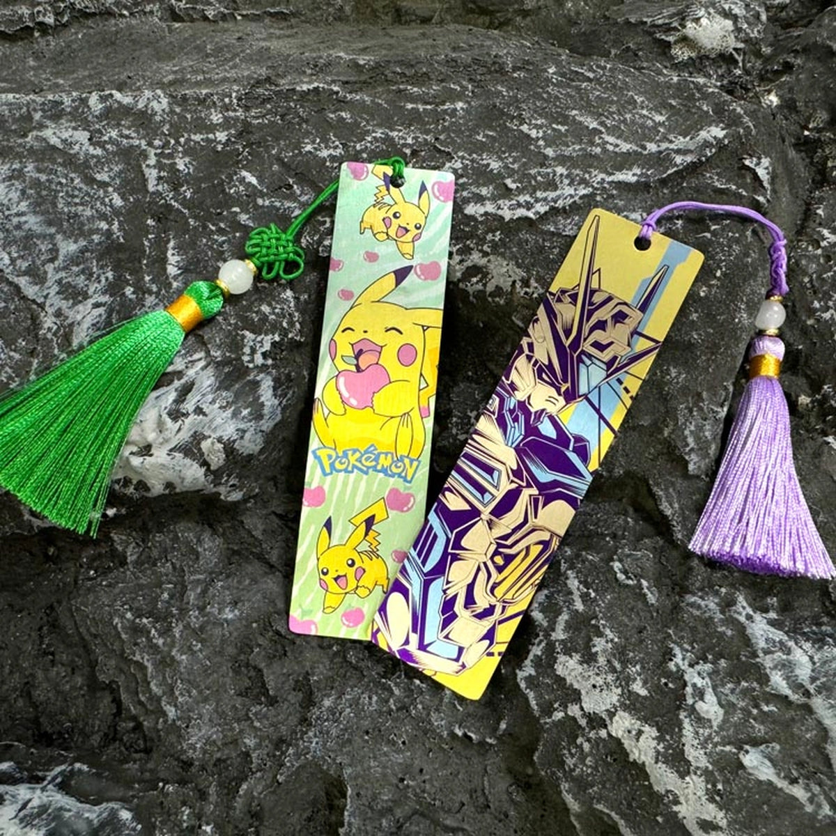 Illustrated Titanium Bookmark: illustrated bookmarks with tassels resting on stone (gallery view 01).
