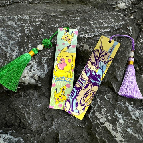 Illustrated Titanium Bookmark: illustrated bookmarks with tassels resting on stone (gallery view 01).