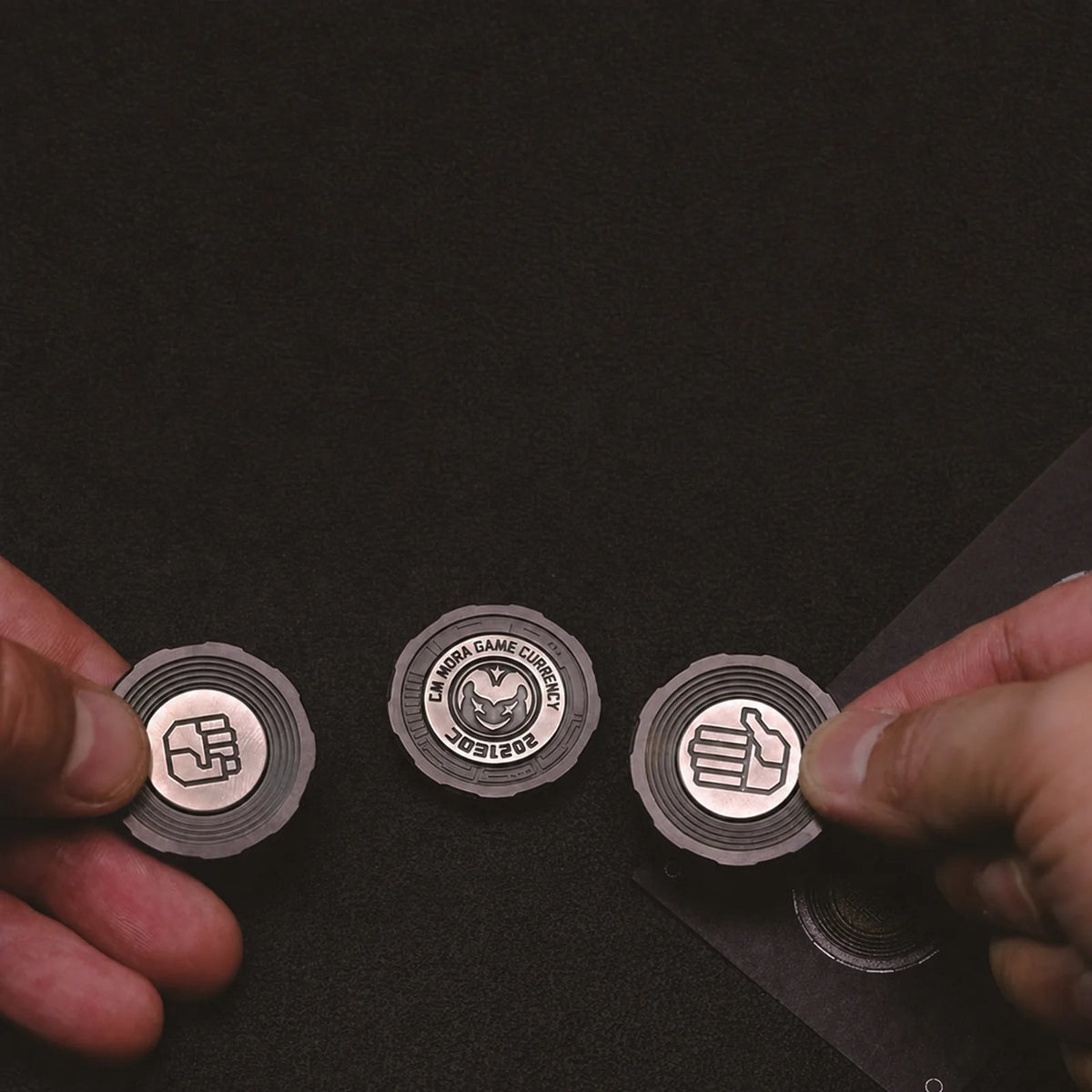 Three Chimago decision coins held for rock paper scissors play