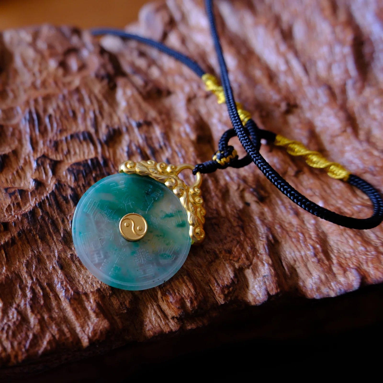 Rotating guardian pendant resting on carved wood with black cord