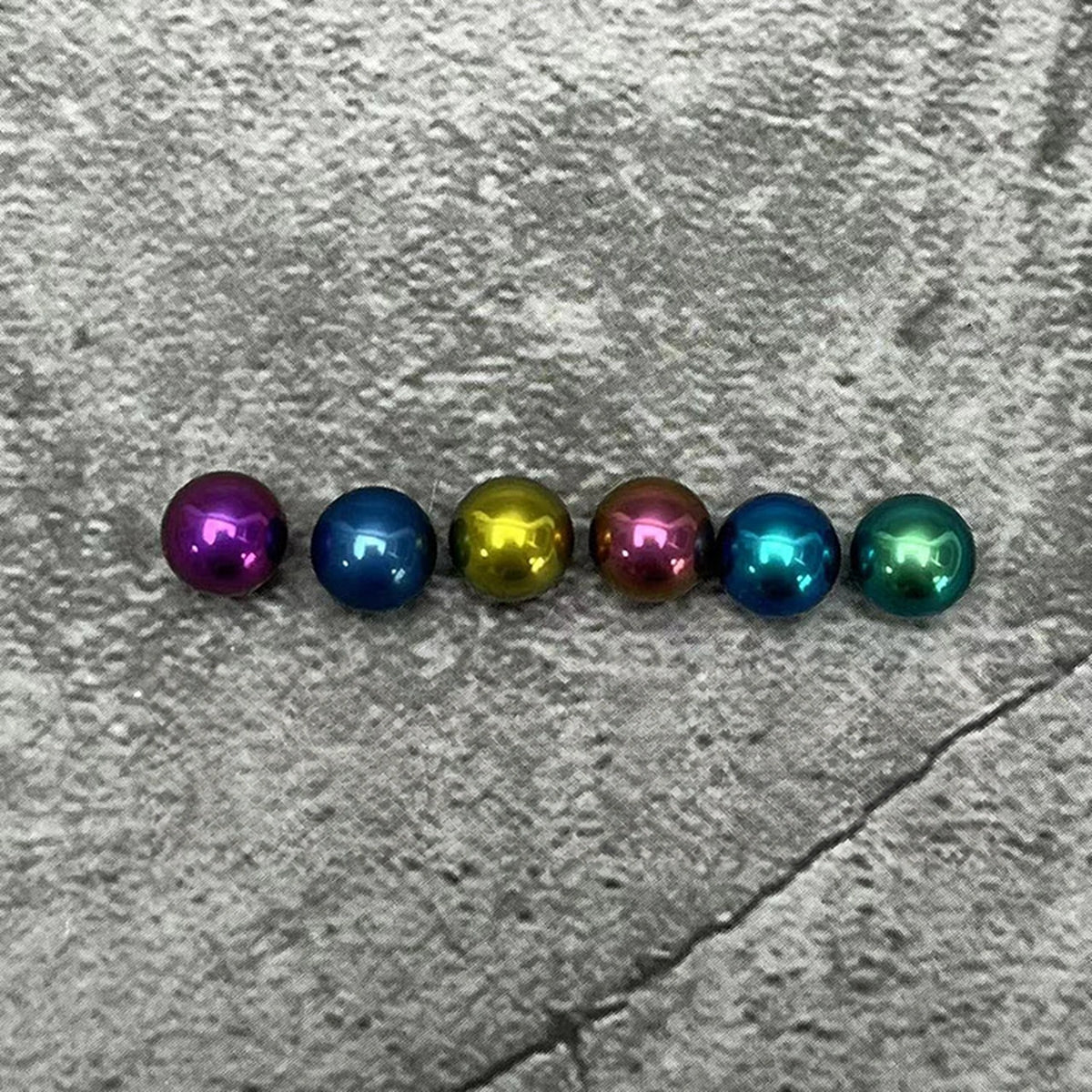 Titanium Spinner Balls: row of plain colored balls on stone (gallery view 02).