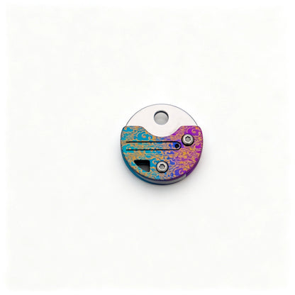 Coin-Shaped Titanium Keychain Knife: round multicolor handle folded on white (gallery view 03).