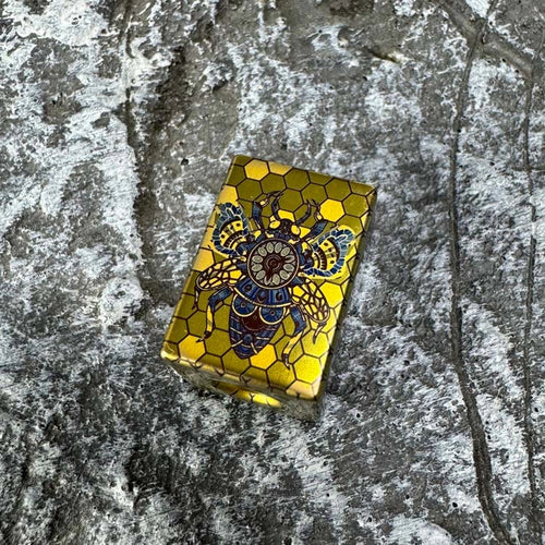 Bee Emperor Titanium Lanyard Bead: bee artwork face resting on stone (gallery view 01).