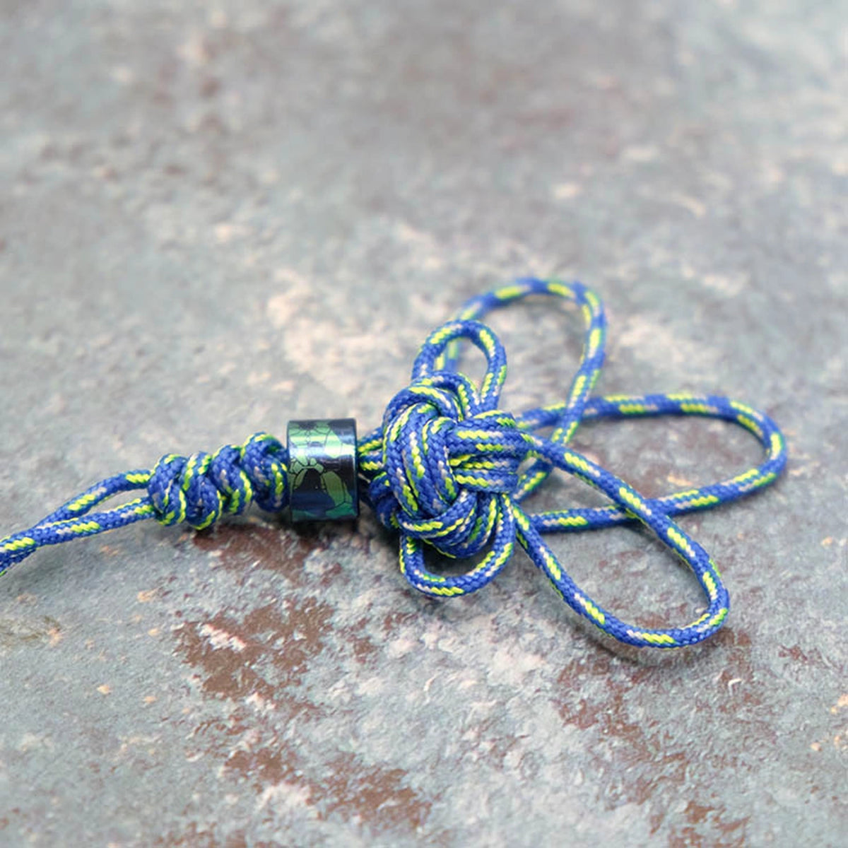 Camouflage Titanium Lanyard Beads: camouflage bead shown on blue yellow cord (gallery view 01).