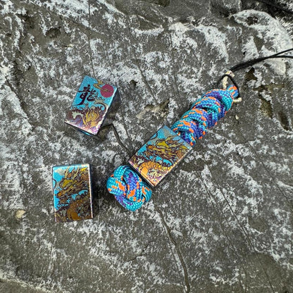 Wave Dragon Titanium Lanyard Bead: dragon artwork beads beside blue woven lanyard (gallery view 01).