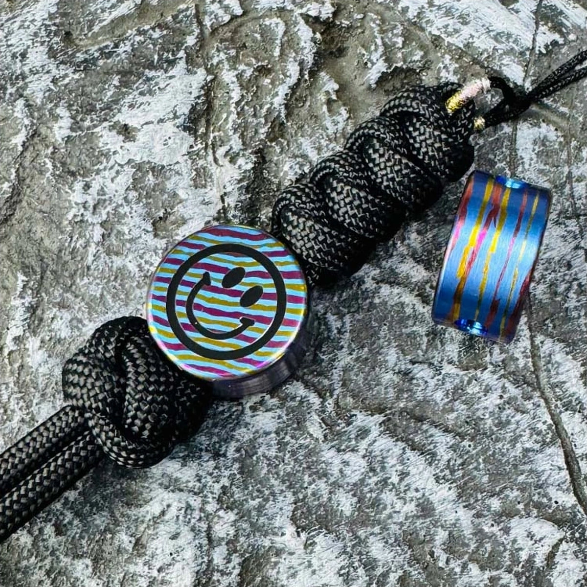 Smiley Face Titanium Lanyard Bead: front and side views on black braided lanyards (gallery view 04).