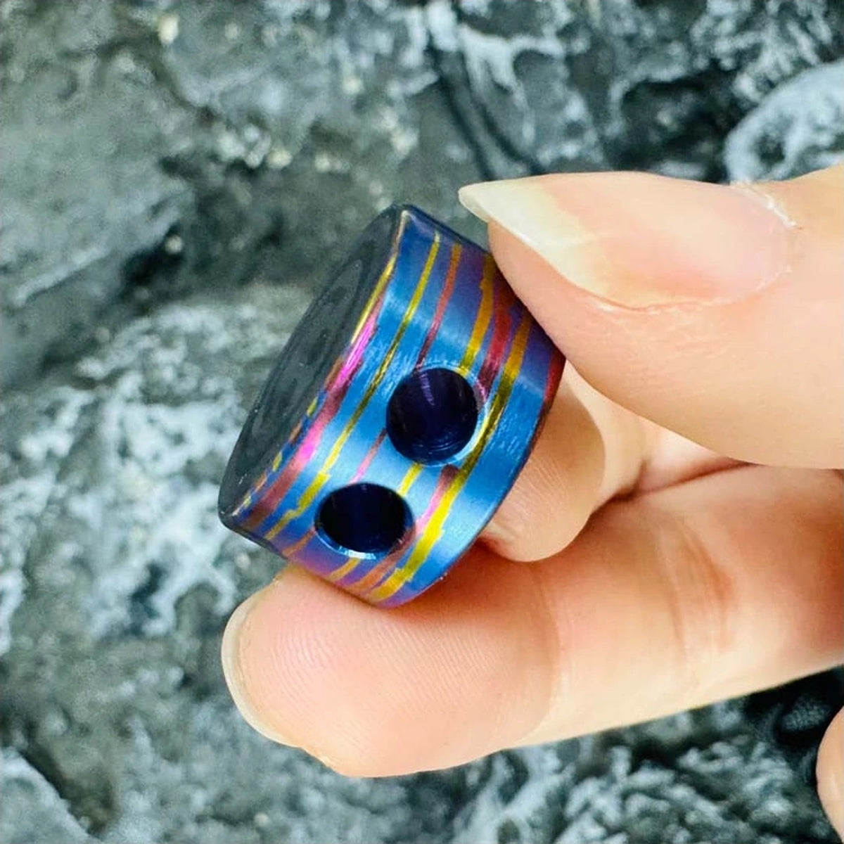 Smiley Face Titanium Lanyard Bead: hand-held side view showing two cord openings (gallery view 02).