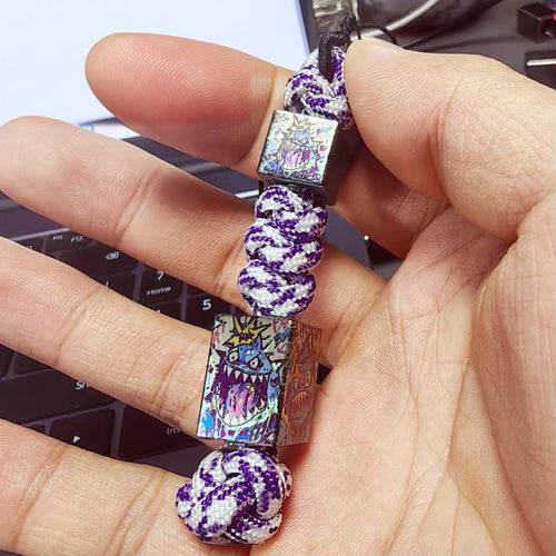 Crazy Shark Titanium Lanyard Beads: hand holding two shark beads on purple braided cord (gallery view 01).