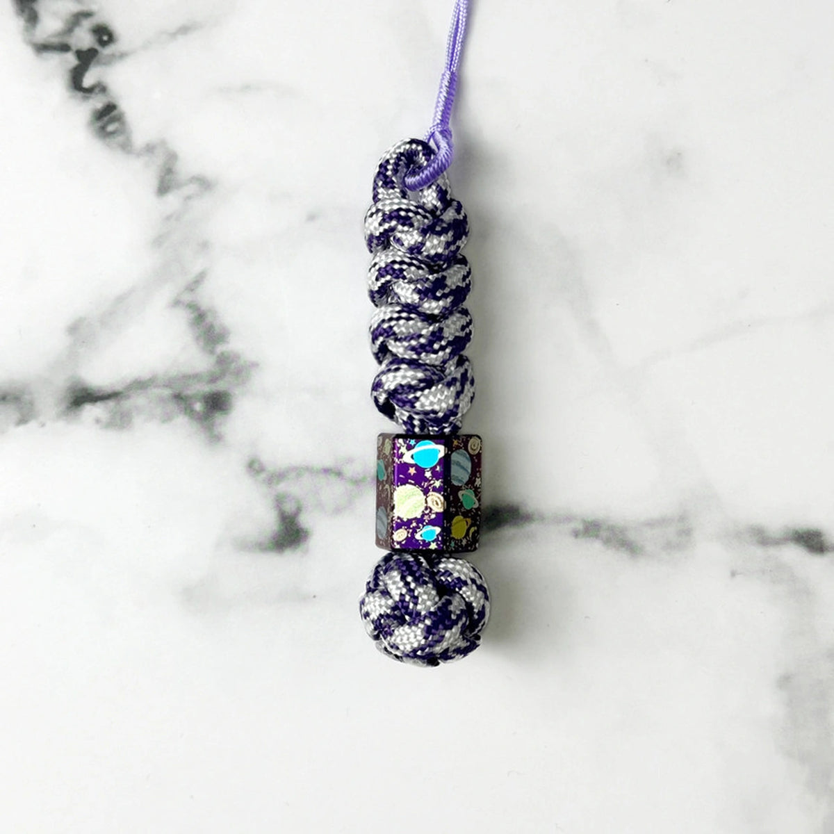 Planet Artwork Titanium Lanyard Beads: hexagonal bead on purple patterned cord (gallery view 14).