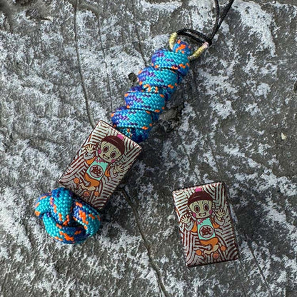 Chiaotzu Artwork Titanium Lanyard Bead: illustrated bead on blue orange cord beside loose bead (gallery view 01).