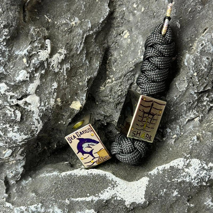 Sea Shark Titanium Lanyard Bead: silver shark bead beside its woven cord (gallery view 04).