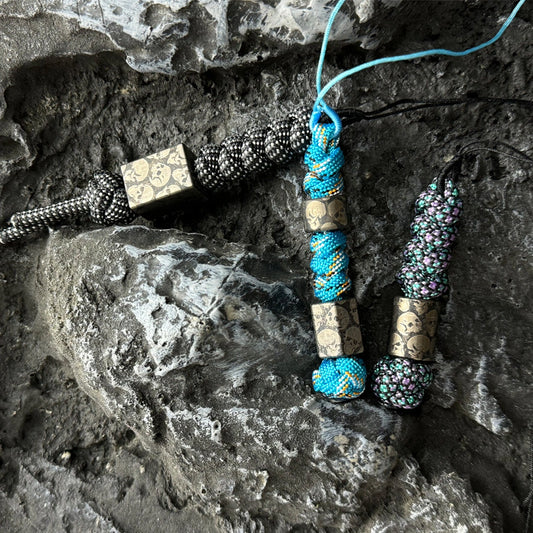Dark Skull Titanium Lanyard Beads: three dark skull bead lanyards on stone (gallery view 01).