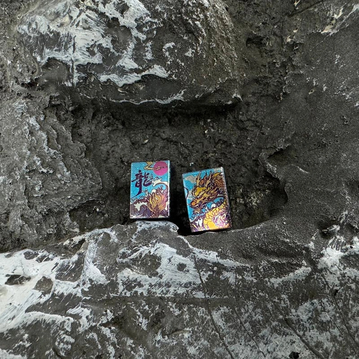 Wave Dragon Titanium Lanyard Bead: two illustrated bead faces resting on stone (gallery view 02).