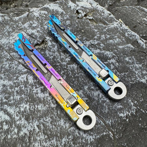 Titanium Keychain Package Opener: two slim multicolor package opener bodies on stone (gallery view 01).