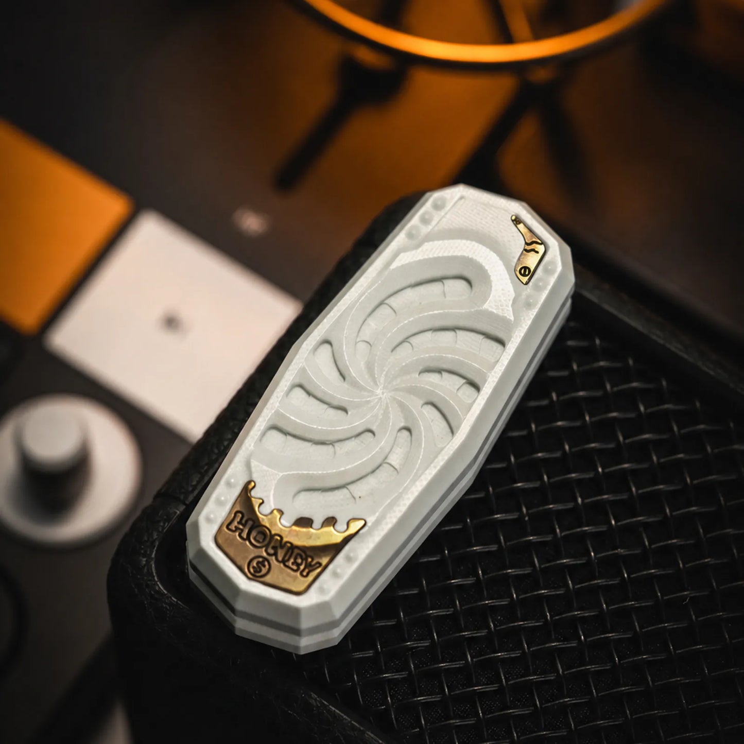 White PEEK mechanical fidget slider with spiral face and metal emblem