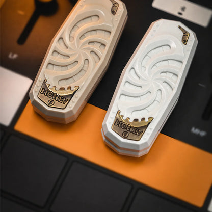 Two white PEEK mechanical sliders displayed on an EDC desk setup