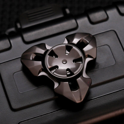 Gunmetal three-lobed spinner with faceted arms and a five-slot circular center