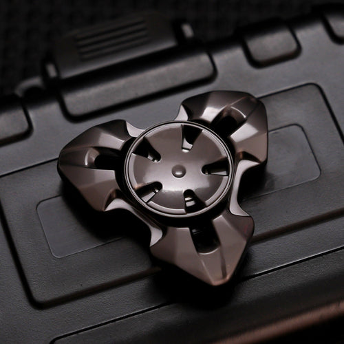 Gunmetal three-lobed spinner with faceted arms and a five-slot circular center