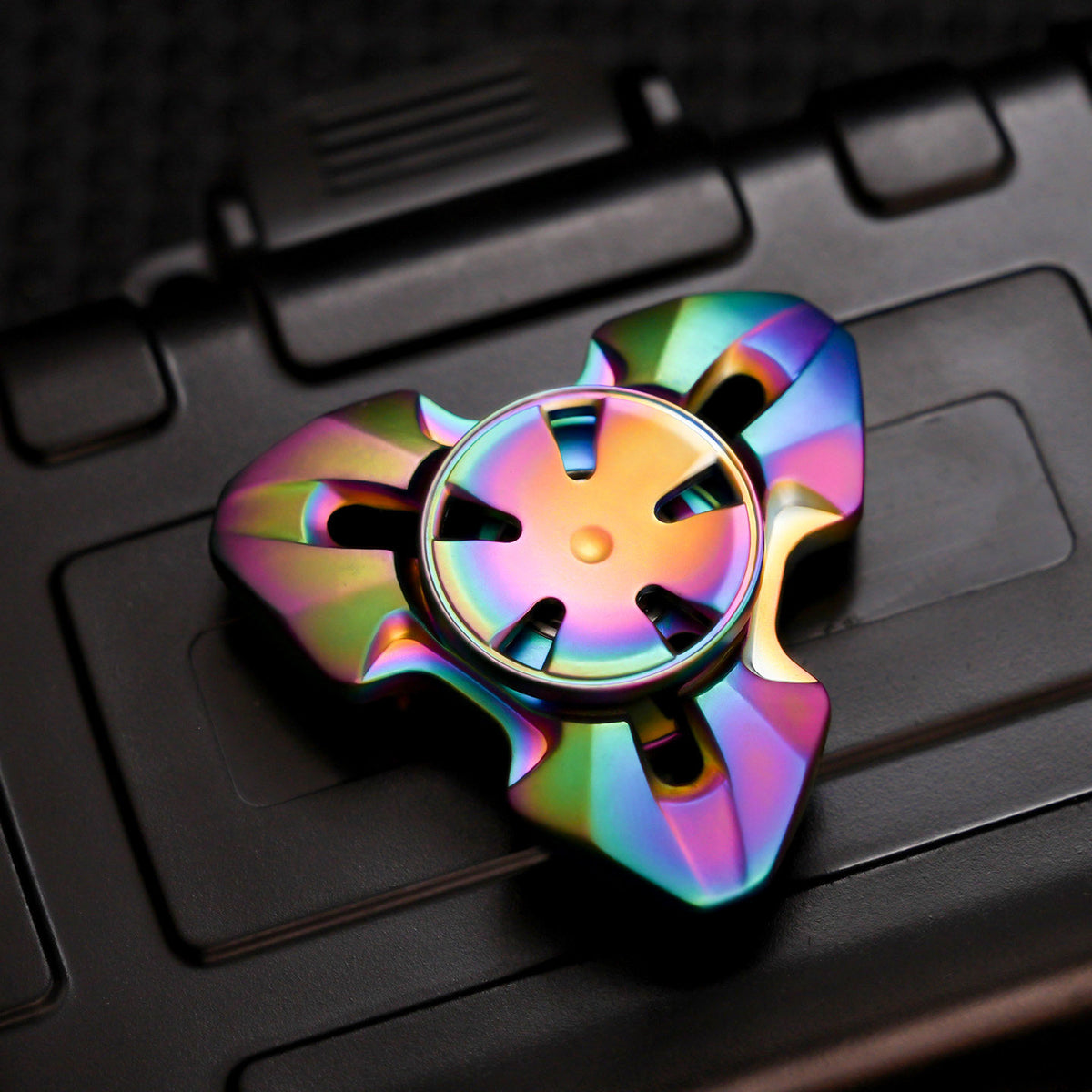 Rainbow three-lobed spinner with faceted arms and a five-slot circular center