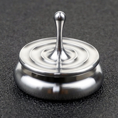 Silver spinning top with concentric ripple rings resting on a rounded metal base.