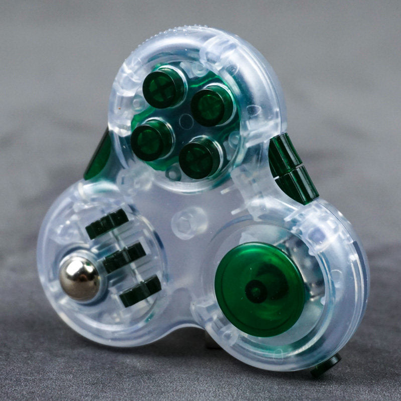 Clear three-lobed triangular fidget toy with green controls and a metal-colored ball beside three wheels.