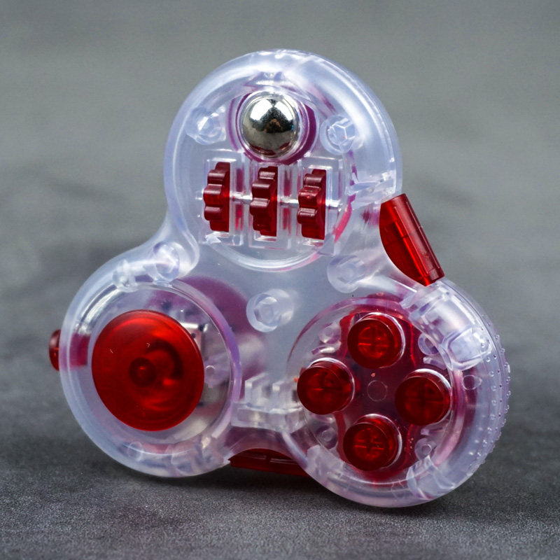 Clear three-lobed triangular fidget toy with red controls, four round buttons and a metal-colored ball.