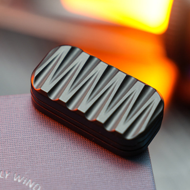 Black three-layer rectangular slider with alternating sculpted grooves on its face.