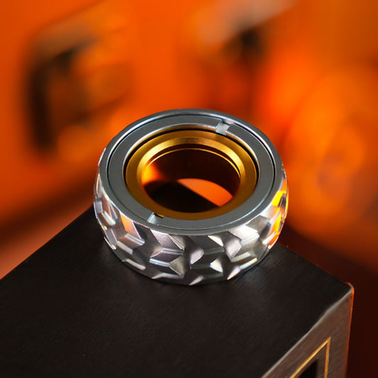 Silver tire-pattern ring with a silver-tone face and gold-tone inner ring, shown on a dark block.
