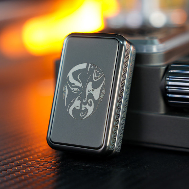 Dark Split-Face slider with a split opera-mask motif, rounded frame and repeating geometric side border; background camera is a photo prop.