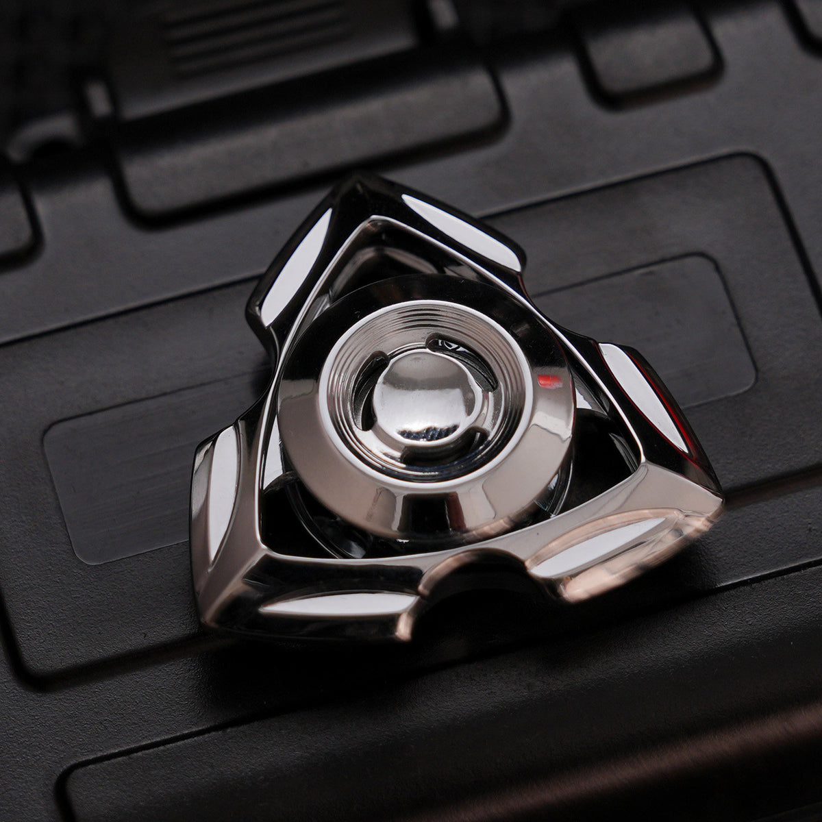 Silver-tone zinc-alloy Siren spinner with a reflective finish, triangular open frame and circular center grip.
