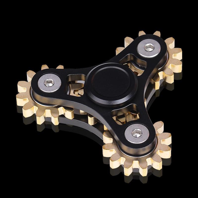 Black triangular spinner with exposed gold-tone gears and a round center cap.