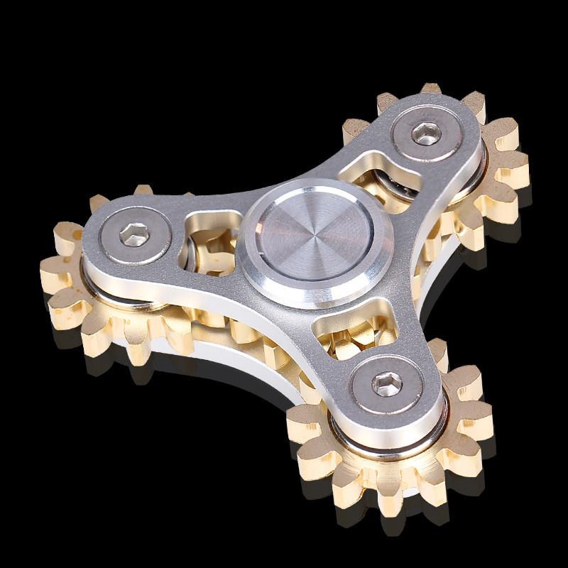 Silver triangular spinner with exposed gold-tone gears and a round center cap.