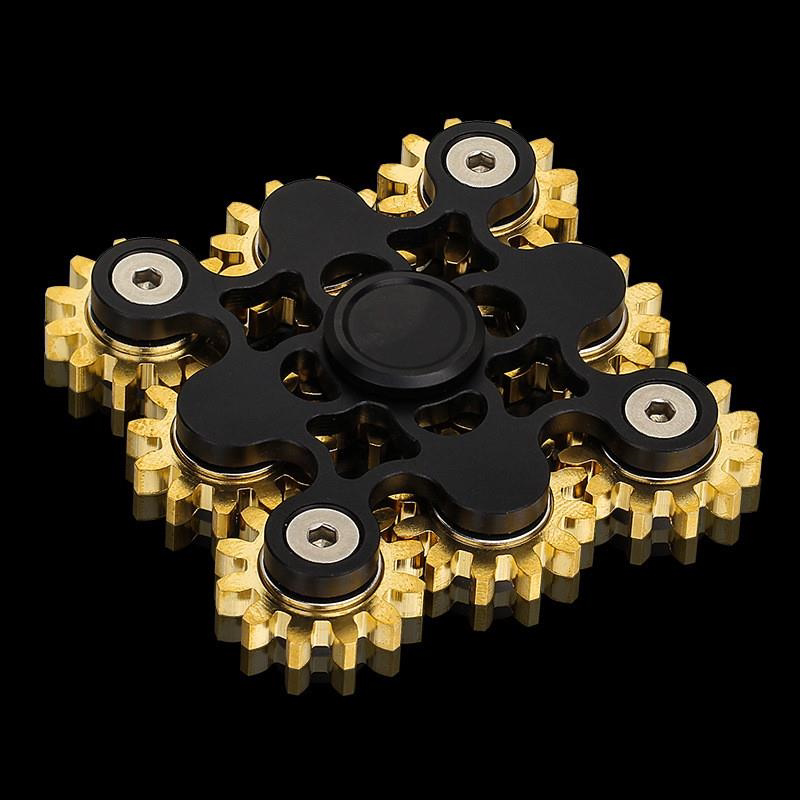 Black square-layout spinner with multiple exposed gold-tone gears.